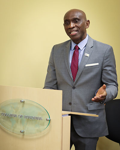 Pat Obi stands at a College of Business branded podium