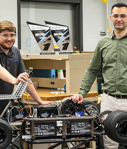 Andrew Miloshoff, standing on the left, and Khair Al Shamaileh work on an evGrand Prix vehicle.