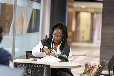 A student sits at a desk. There are open books in front of them