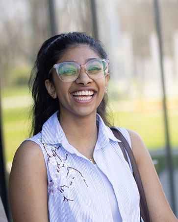 A student stands outside and smiles