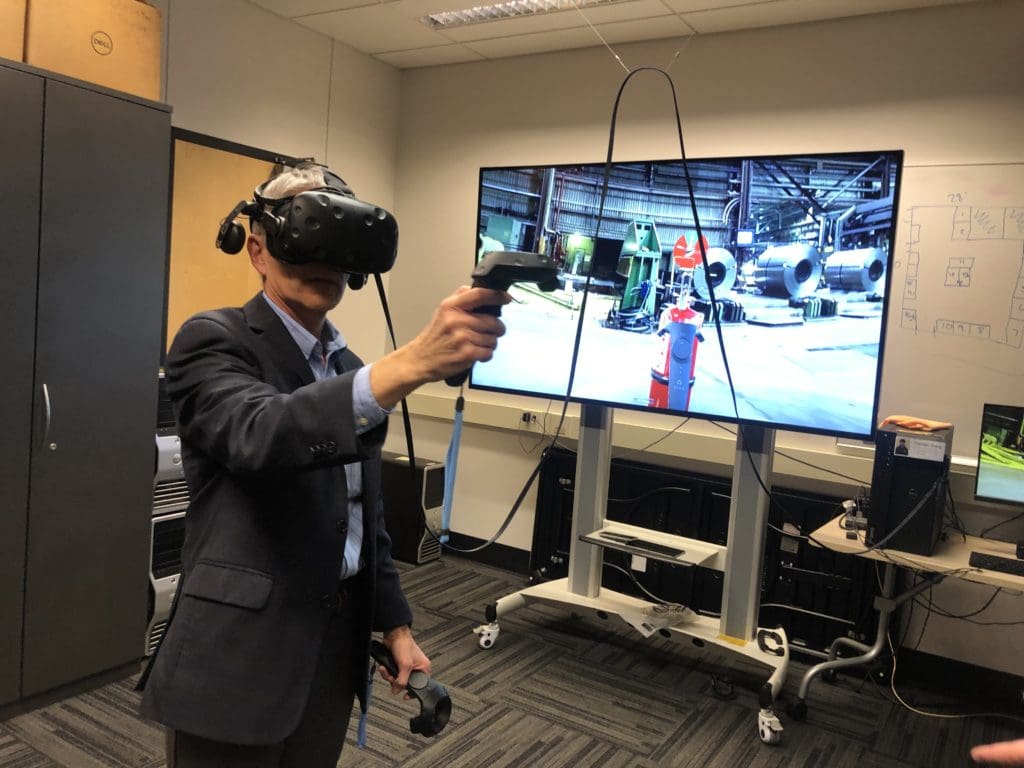 A man in a suit uses a VR headset.