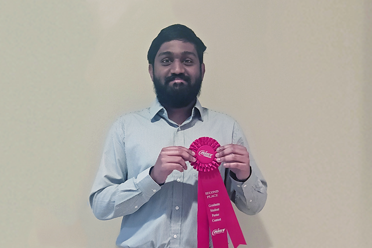 A student poses with a second place ribbon