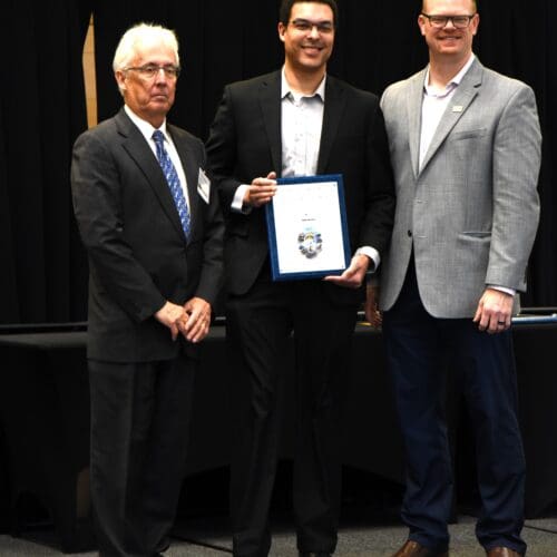 3 men posing with an award