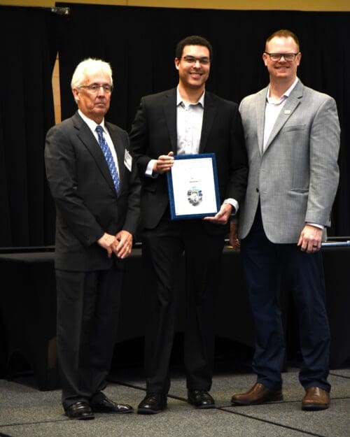 3 men posing with an award