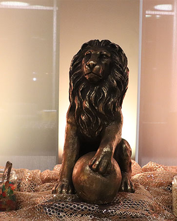 A bronze sculpture of a lion with its foot on a ball.