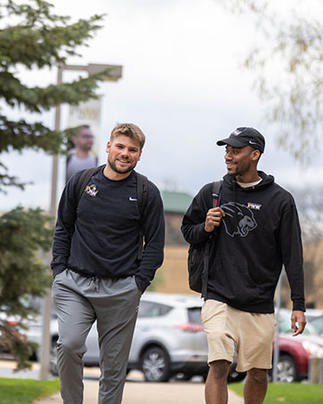 Two College of Business students walk together outside