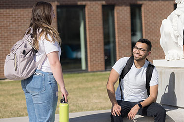 Two students sit outside on the PNW Hammond Campus