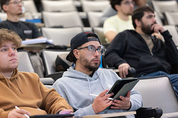 A student in a gray sweatshirt looks ahead in class