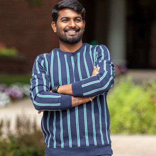 A PNW student stands outdoors on campus