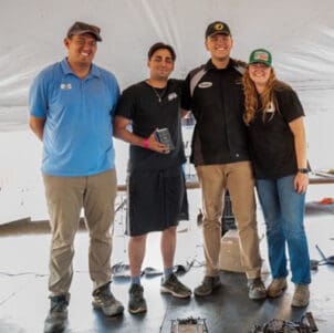 Four people pose together with an award