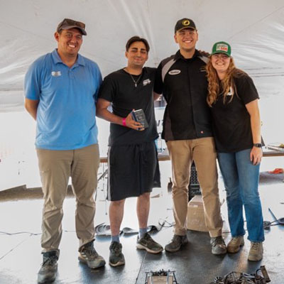 Four people pose together with an award