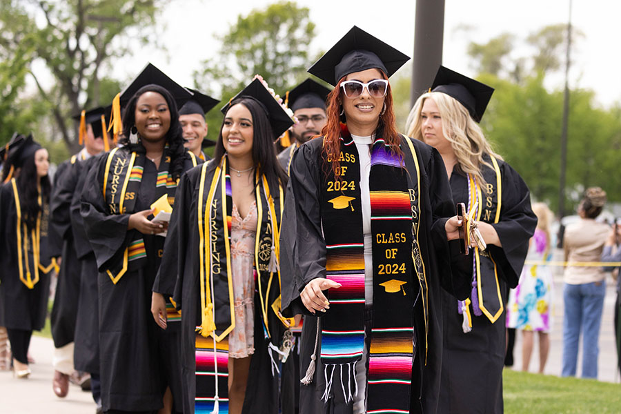 A group of students walk in during a commencement ceremony