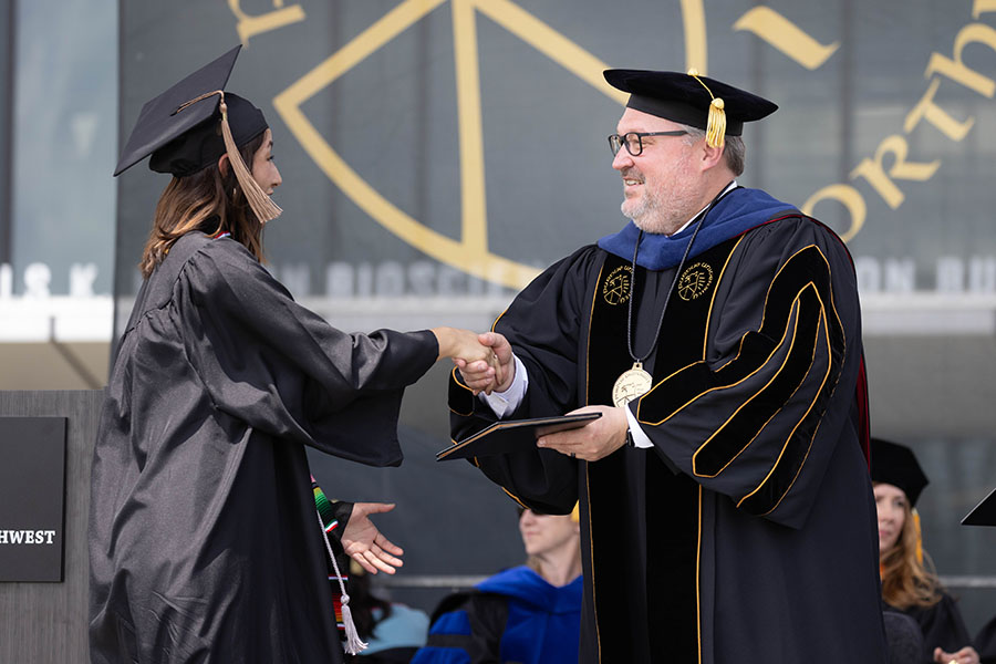 PNW Chancellor Kenneth C. Holford hands a degree to a graduating student.