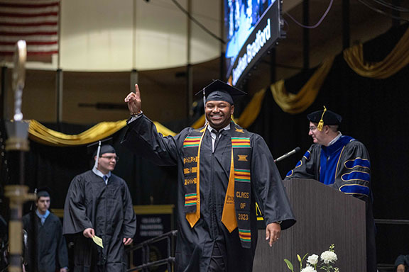 A PNW graduation raises a hand in celebration at commencement