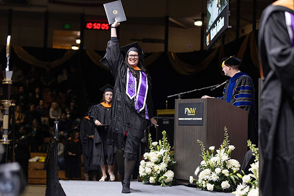 A PNW graduate raises her degree at Fall 2024 Commencement