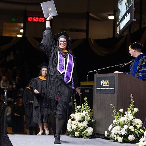 A PNW graduate raises her degree at Fall 2024 Commencement