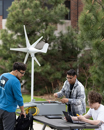 Three students work on a project outside