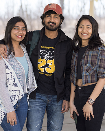 Three students pose together outdoors