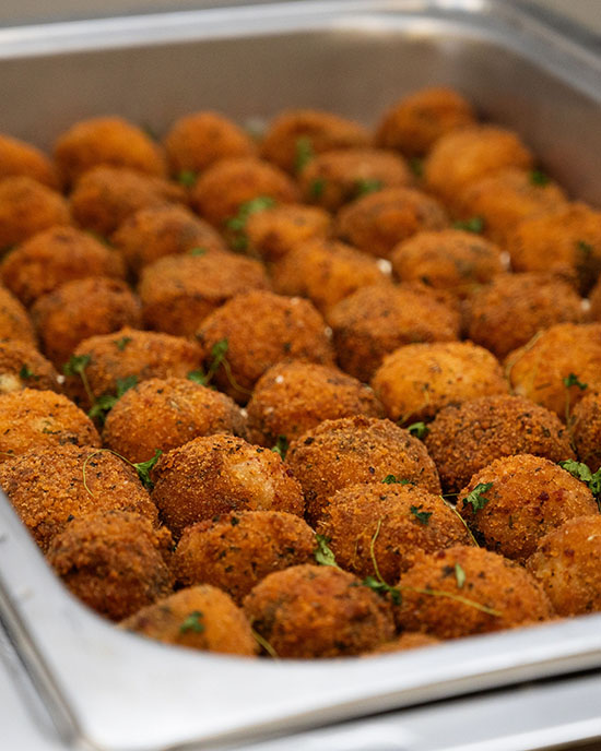 Fried balls of food lined up in a serving tray.