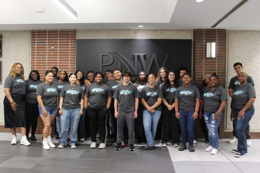 Group of students and staff standing in front of a PNW sign