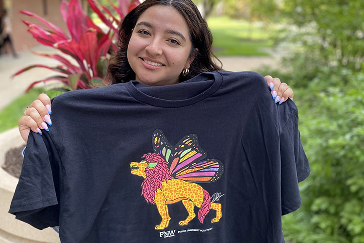 A student holds a t-shirt featuring a lion with fairy wings