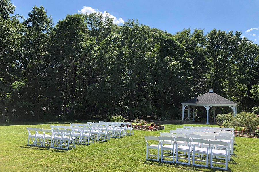 White chairs in rows in front of the Gabis Arboretum Rose Pavilion