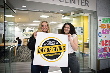 PNW Students hold the Day of Giving poster sign