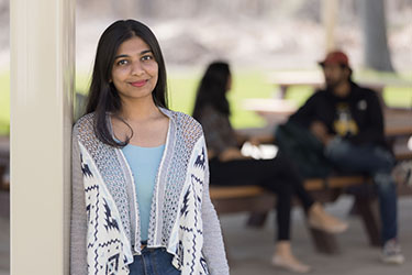 A student leans against an outdoor gazebo.