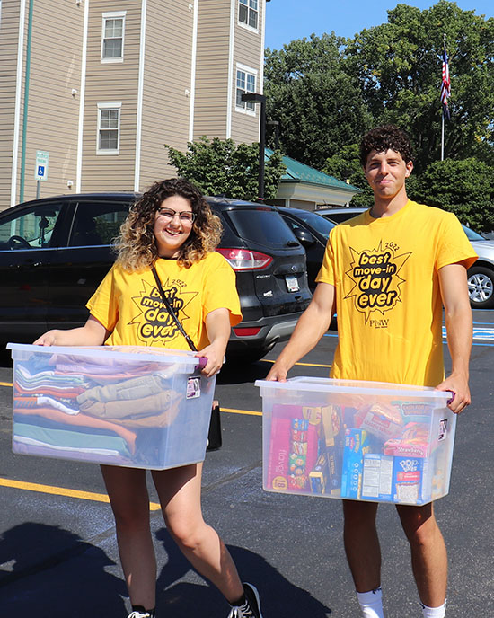 Two people in yellow "Best Move in Day Ever" t-shirts carry plastic totes