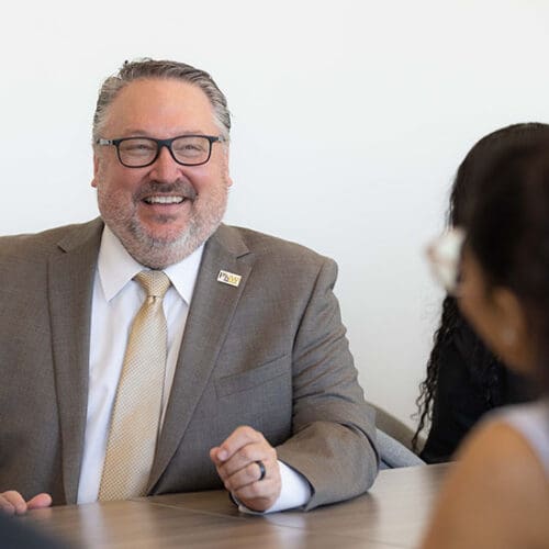 PNW chancellor Chris Holford talks with students at a conference table.