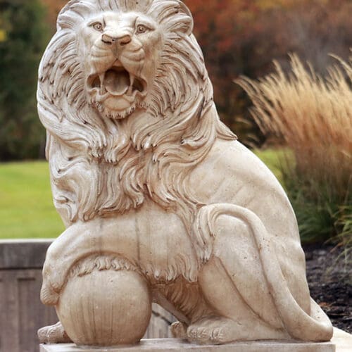 A statue of a lion in front of fall foliage