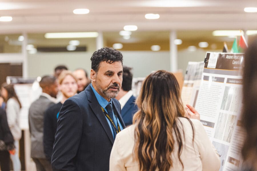 Faculty speaking with a student during a poster presentation.