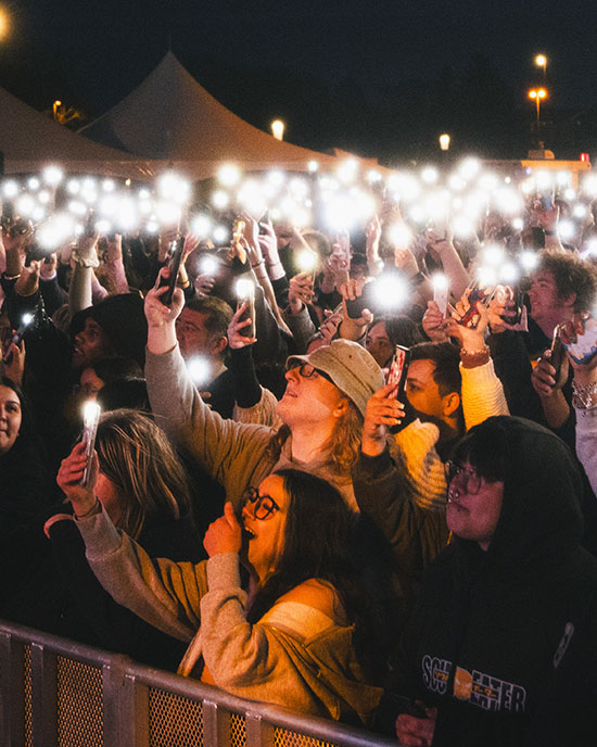 Students gather for PNW's annual Roaring Loud concert. They are all holding up cellphone flashlights.