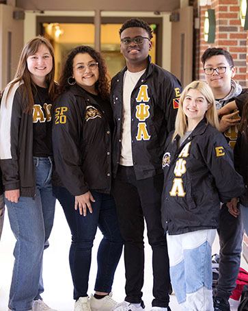 PNW students in matching jackets pose in a hallway