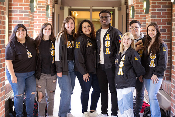 PNW students in matching jackets pose in a hallway