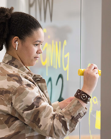 A student decorates windows for PNW Homecoming.