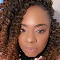 Headshot of Dakita Jones in a pearl necklace and pink jacket