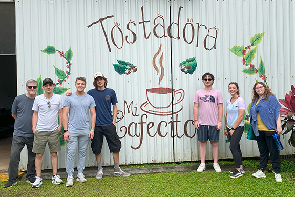 Students and Honors College Dean Jon Swarts pose together outside of a coffee shop