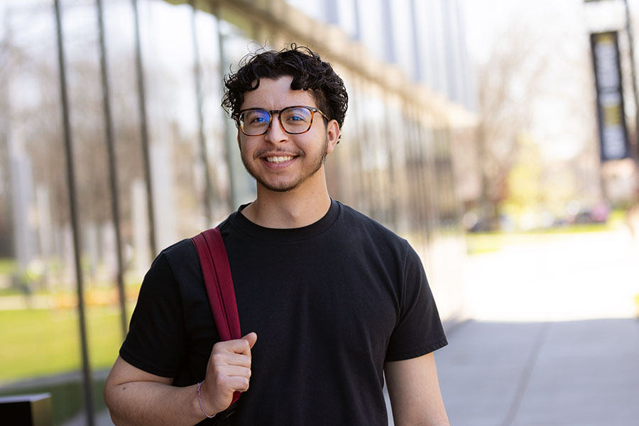 A PNW student stands outdoors with a backpack