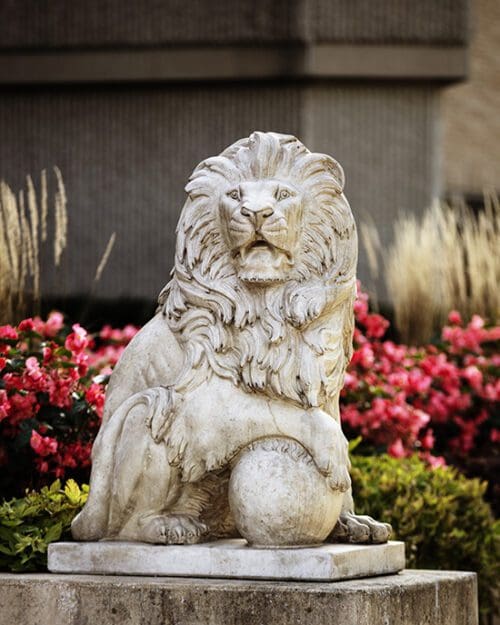 A lion statue in front of flowers