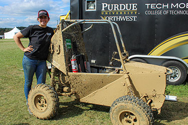 A PNW student poses next to a Baja car.