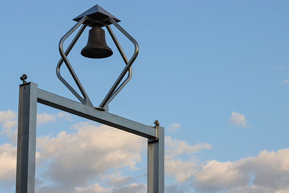 The top of PNW's Bell Tower with a cloudy blue sky in the background.