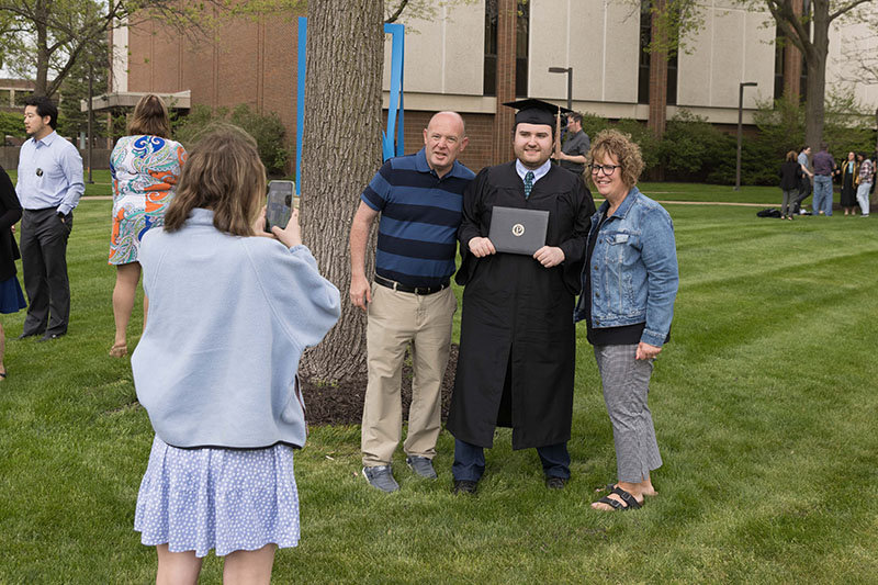 A student poses with their parents during a commencement ceremony