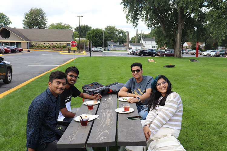 Four students sit together during a welcome week picnic