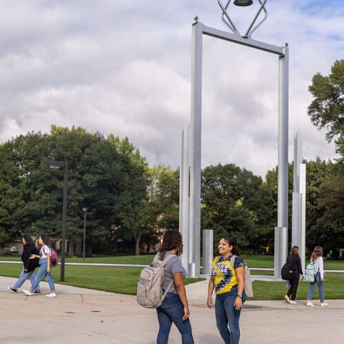 Students stand around the bell tower and talk