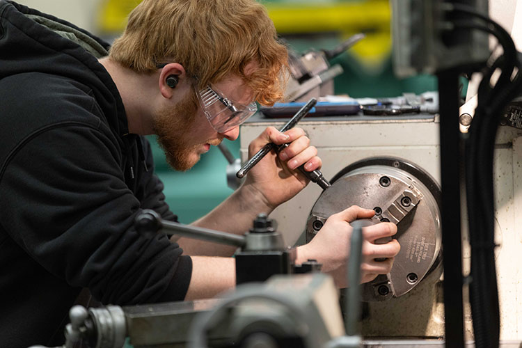 A PNW student works on a lathe