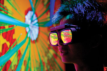 A person wearing reflective goggles looks at a blast furnace simulation