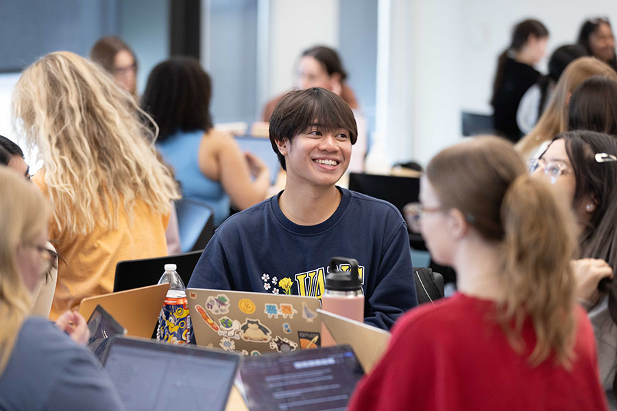 Student smiles as he sits in a group at a table for a study group