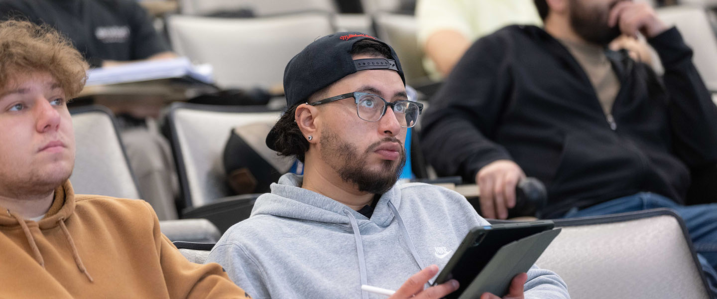 A student in a gray sweatshirt looks ahead in class