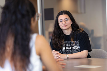 Two PNW students talk at a conference table.